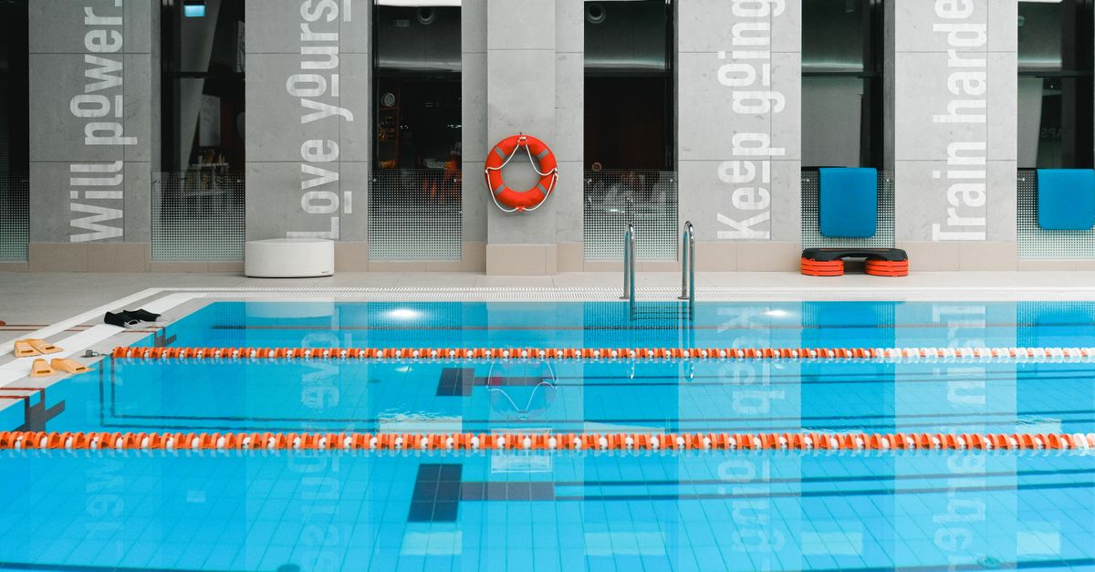 A modern indoor swimming pool with motivational quotes on the walls and clear water.