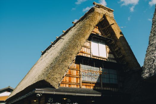 Gorgeous shot of a traditional Japanese thatched roof house under a clear blue sky.