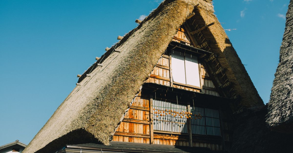 Gorgeous shot of a traditional Japanese thatched roof house under a clear blue sky.
