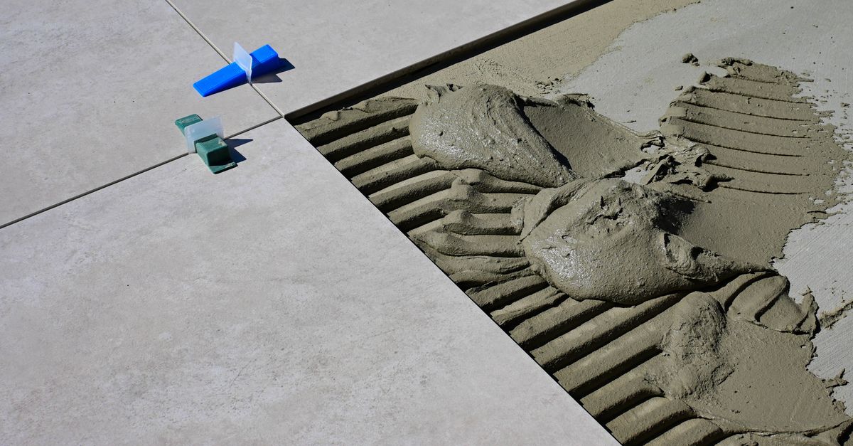 Close-up of wet cement and tile spacers during floor tile installation.