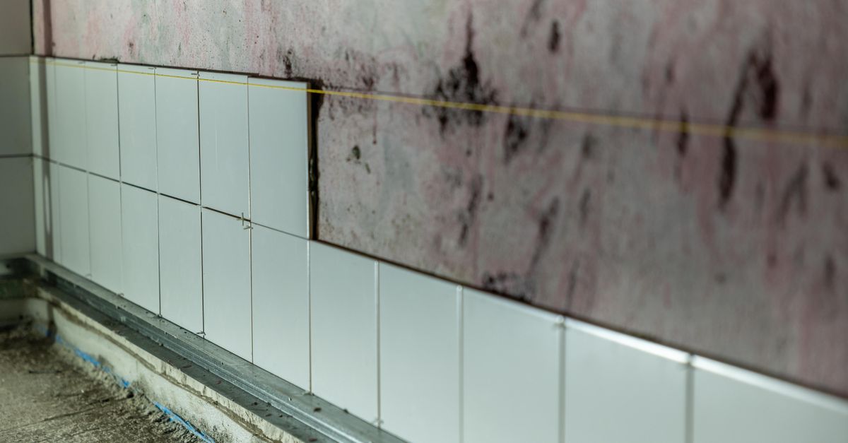 Close-up of partially tiled wall in a construction area, showcasing incomplete renovation work.