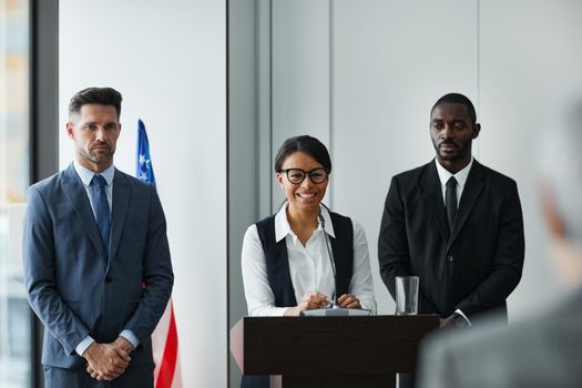 Diverse leaders at a conference podium with US flag in the background.