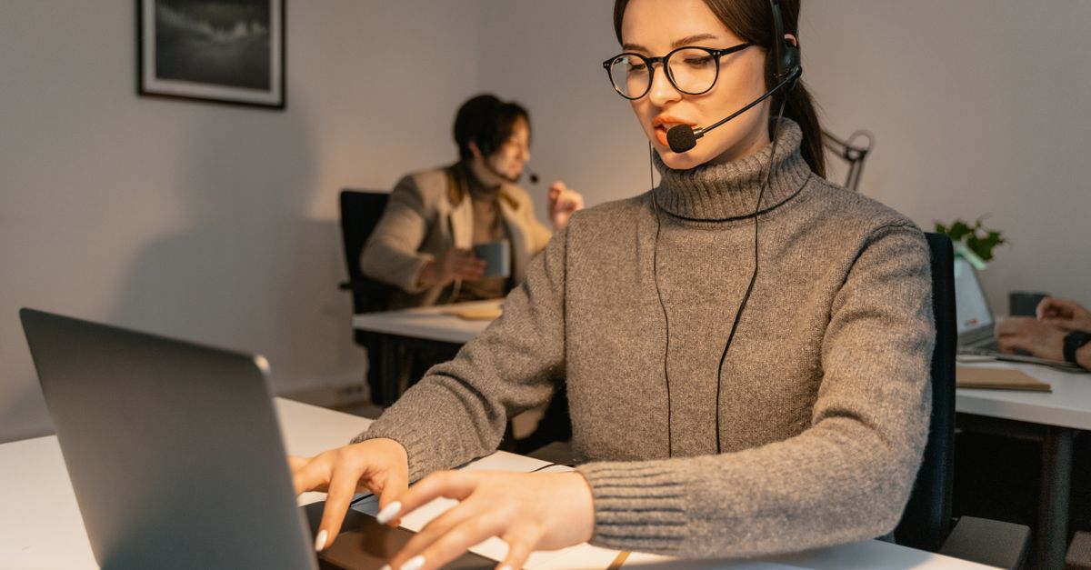 Two call center agents providing customer service in a modern office environment.