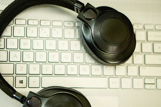 Close-up of black headphones resting on a laptop keyboard, captured from above.