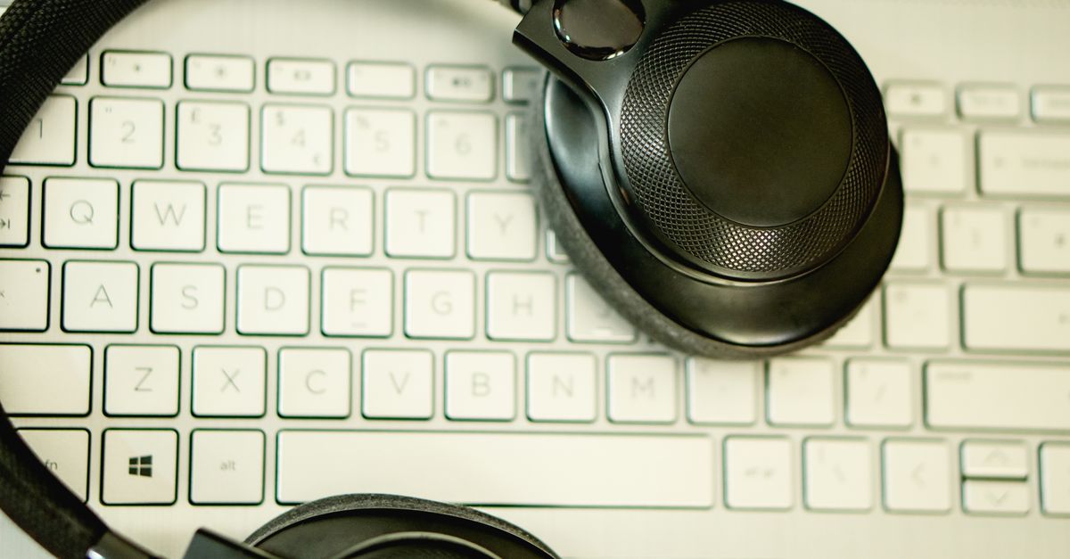 Close-up of black headphones resting on a laptop keyboard, captured from above.