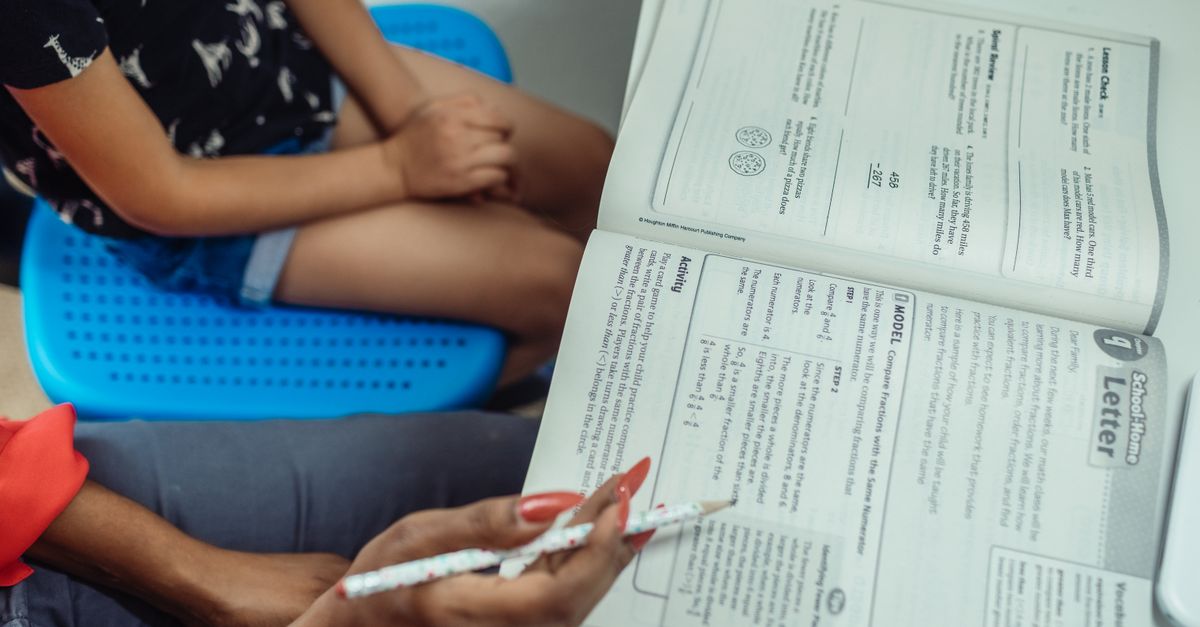 An educational scene with a teacher guiding a student through a textbook.