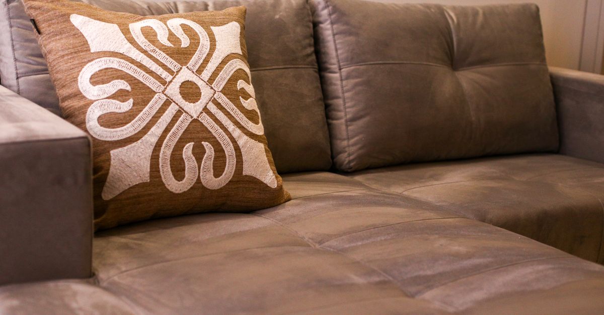 A close-up of an elegant gray sofa with an artistic decorative cushion in a modern living room.