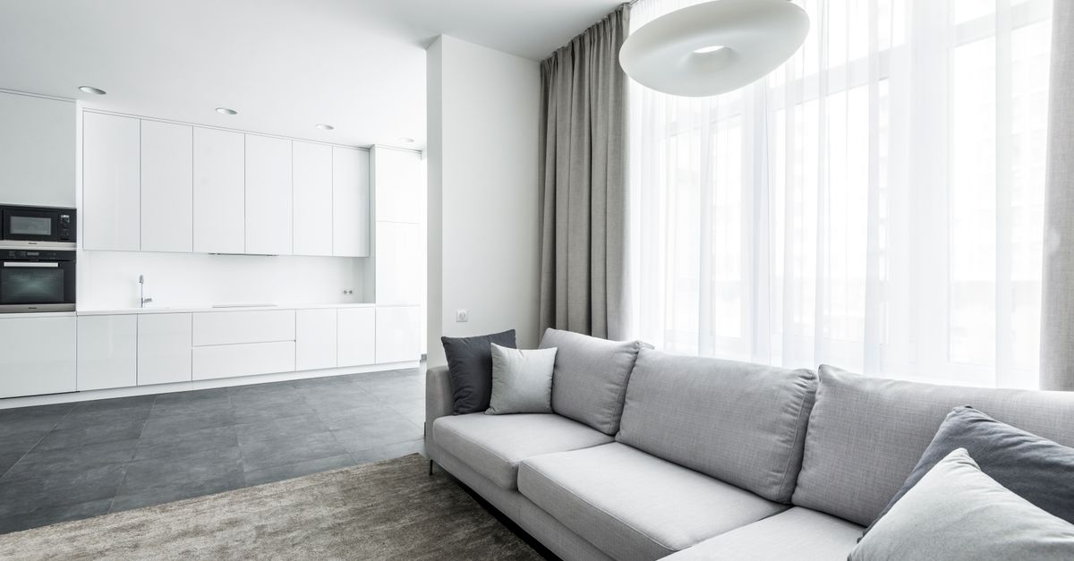 Bright modern living area featuring a cozy sofa and minimalist kitchen background.