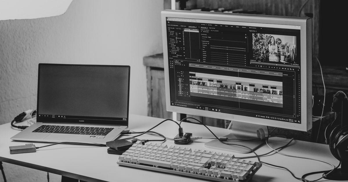 A monochrome workspace setup featuring a laptop and monitor for video editing.