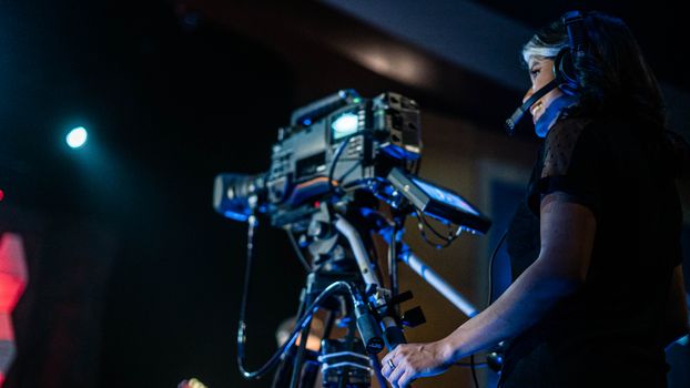 Low angle of happy woman in headset smiling and recording video of music show