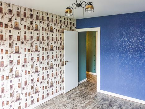 A modern room featuring a blue accent wall, unique patterned wallpaper, and contemporary lighting.
