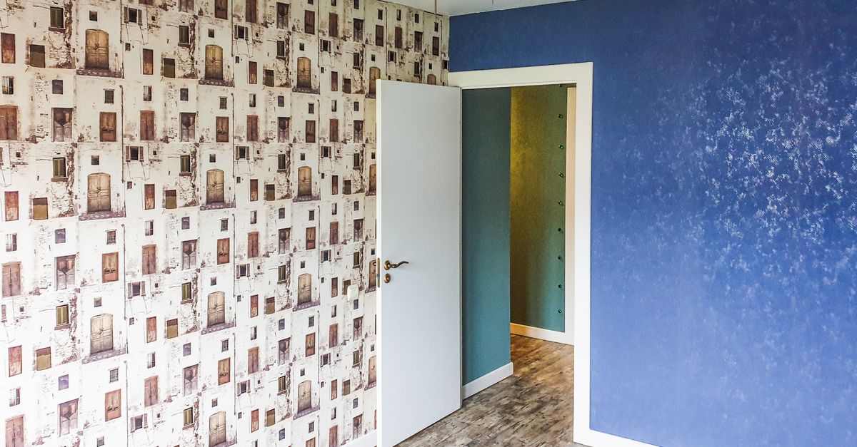 A modern room featuring a blue accent wall, unique patterned wallpaper, and contemporary lighting.