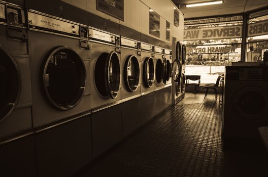 Sepia-toned image of a laundromat interior showcasing a row of classic washing machines.