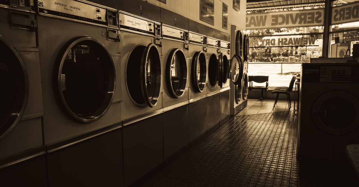 Sepia-toned image of a laundromat interior showcasing a row of classic washing machines.