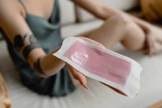 Close-up of a woman's hand holding a hair removal wax strip. Perfect for beauty and skincare content.