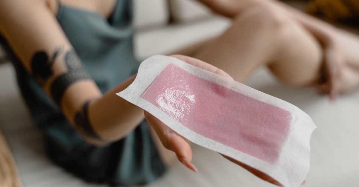 Close-up of a woman's hand holding a hair removal wax strip. Perfect for beauty and skincare content.