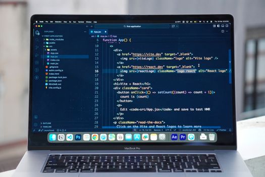A MacBook Pro displaying code editor on a rooftop setting in daylight, ideal for a remote work lifestyle.