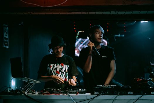 Two DJs performing with equipment in a vibrant nightclub setting, exuding party vibes.