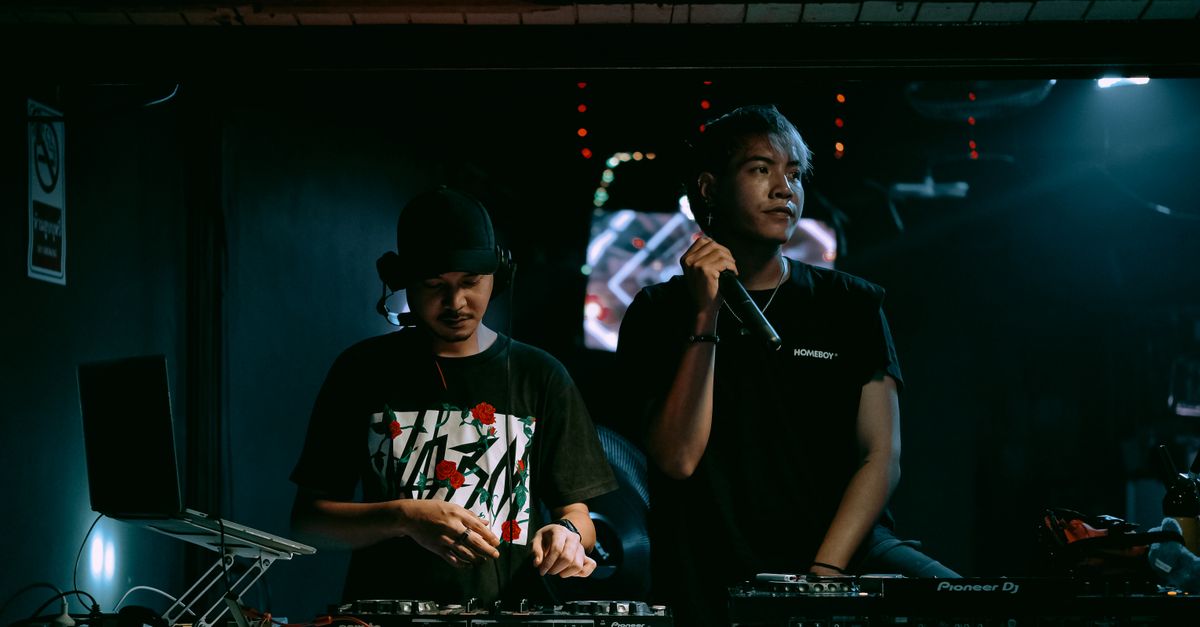 Two DJs performing with equipment in a vibrant nightclub setting, exuding party vibes.