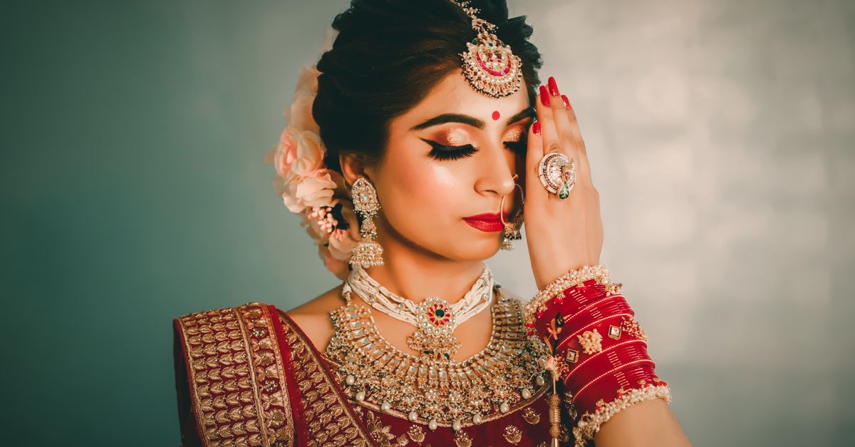Young ethnic female with bright makeup and black eyeliner in national costume closing eyes