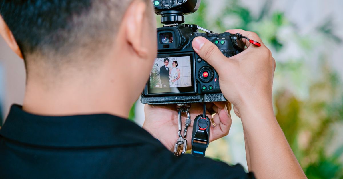 A photographer focuses on capturing a wedding couple using a digital camera during a ceremony.