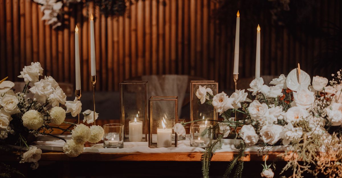 A sophisticated wedding table setup featuring candlelight and white floral arrangements, creating a romantic ambiance.