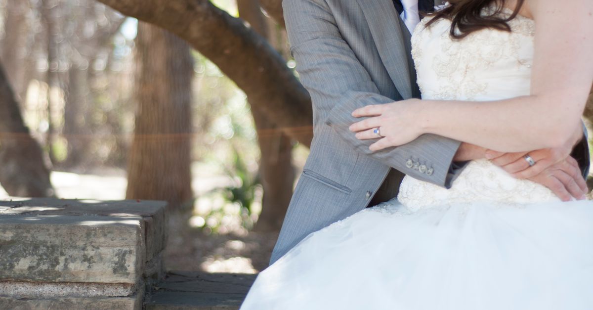 A close-up of a couple embracing on their wedding day in an outdoor setting.