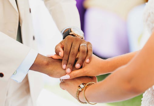 A symbolic gesture of unity, showing hands interlocked at a wedding ceremony.
